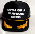 Black cap with 'Faith of a Mustard Seed' text and mustard seed designs on a white background